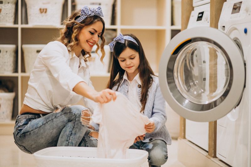 Mother with daughter doing laundry at self serviece laundrette